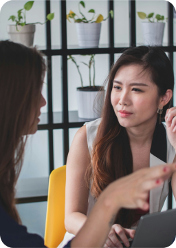 Deux femmes discutant d'un projet, symbolisant la collaboration pour atteindre les objectifs professionnels.