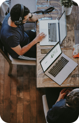 Deux personnes travaillant sur des ordinateurs portables, illustrant la collaboration et la création de projets dans notre portfolio