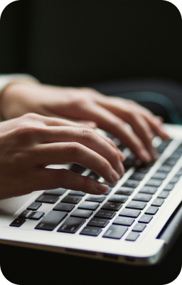 Mains tapant sur un clavier d'ordinateur portable, illustrant la création de projets dans notre portfolio